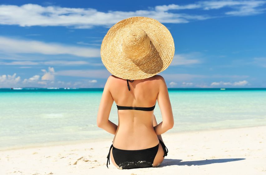 Jolie femme de dos avec un chapeau sur une plage