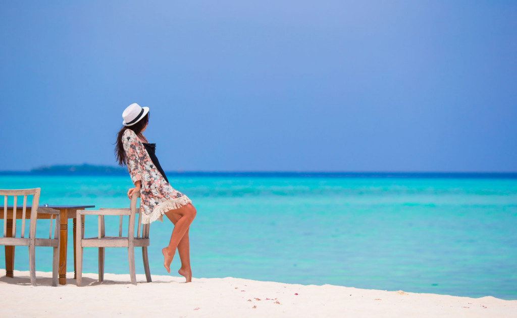 Belle jeune femme avec un chapeau au bord d'une plage