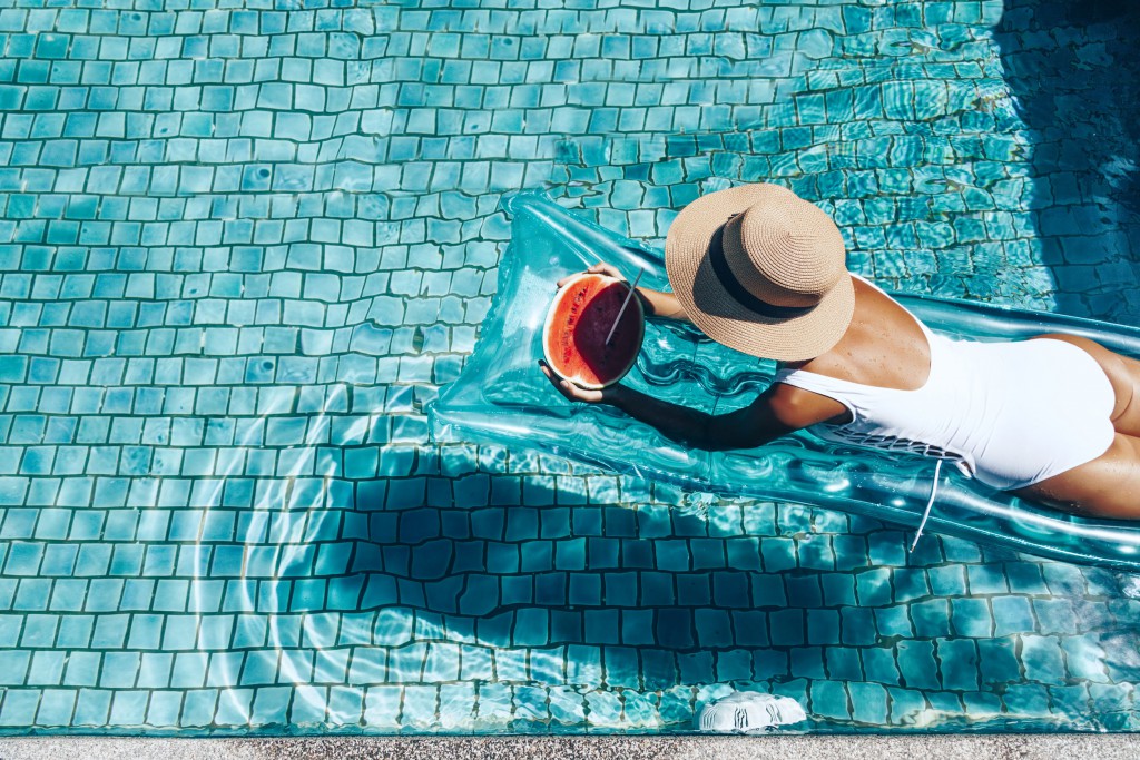 Fille flottant sur un matelas de plage avec une pastèque